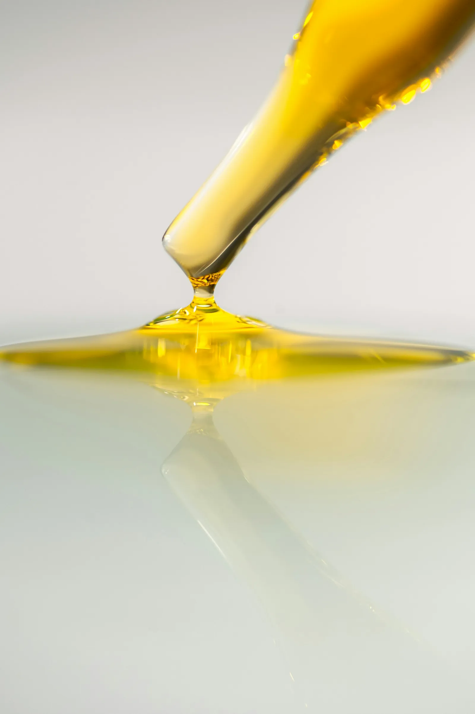 Golden refined oil being poured into a glossy pool